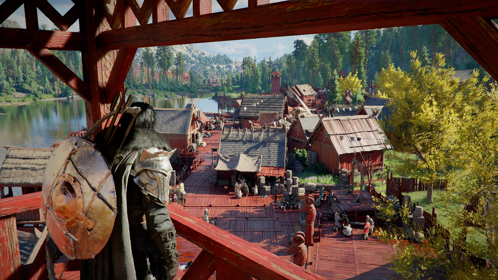A view from a wooden balcony over a red-walled lakeside settlement and forested hills.
